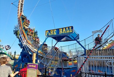A colorful amusement park ride with several excited people enjoying the experience as it spins and ascends.